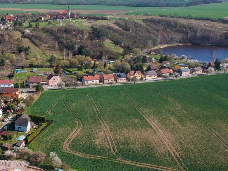 Dřetovice vu du ciel : l'église Saint-Venceslas sur la colline, l'étang et la rue principale du village